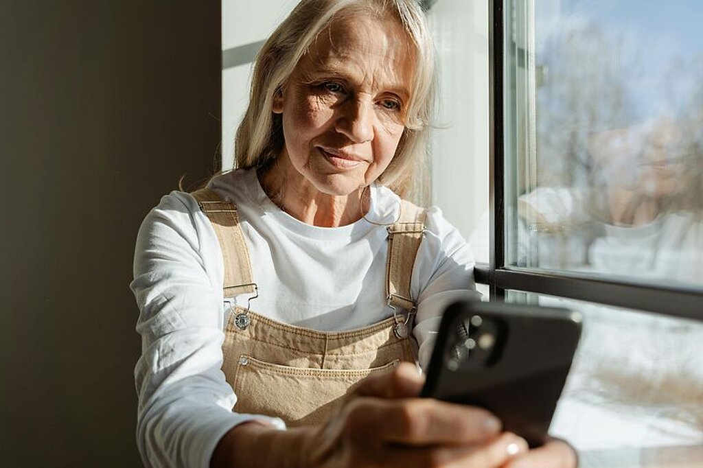 Frau mittleren alters schaut in ihr Mobiltelefon.
