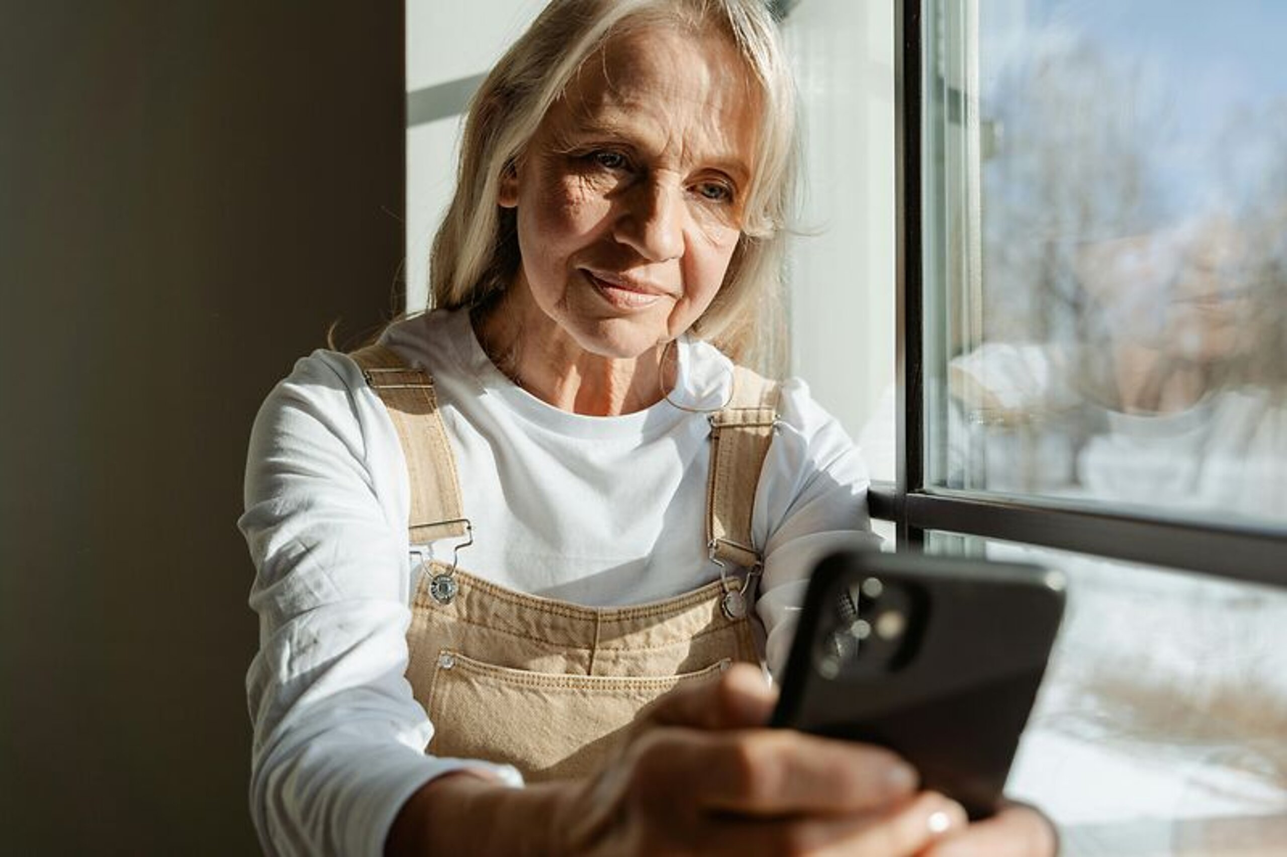Frau mittleren alters schaut in ihr Mobiltelefon.